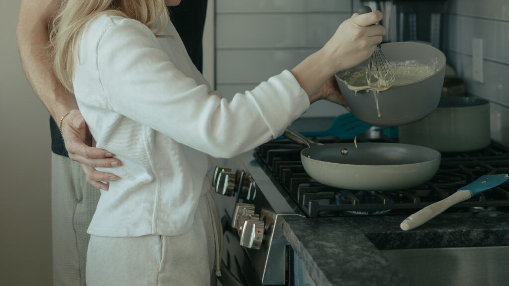 Bride and groom pouring pancake mix onto the stove top on their elopement morning