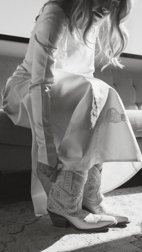 Bride sliding on her cowgirl boots as she gets ready for her elopement