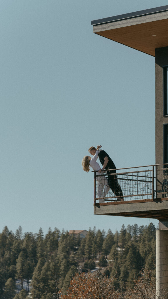 Bride and groom standing on the edge of Airbnb balcony on, snuggled up on elopement day