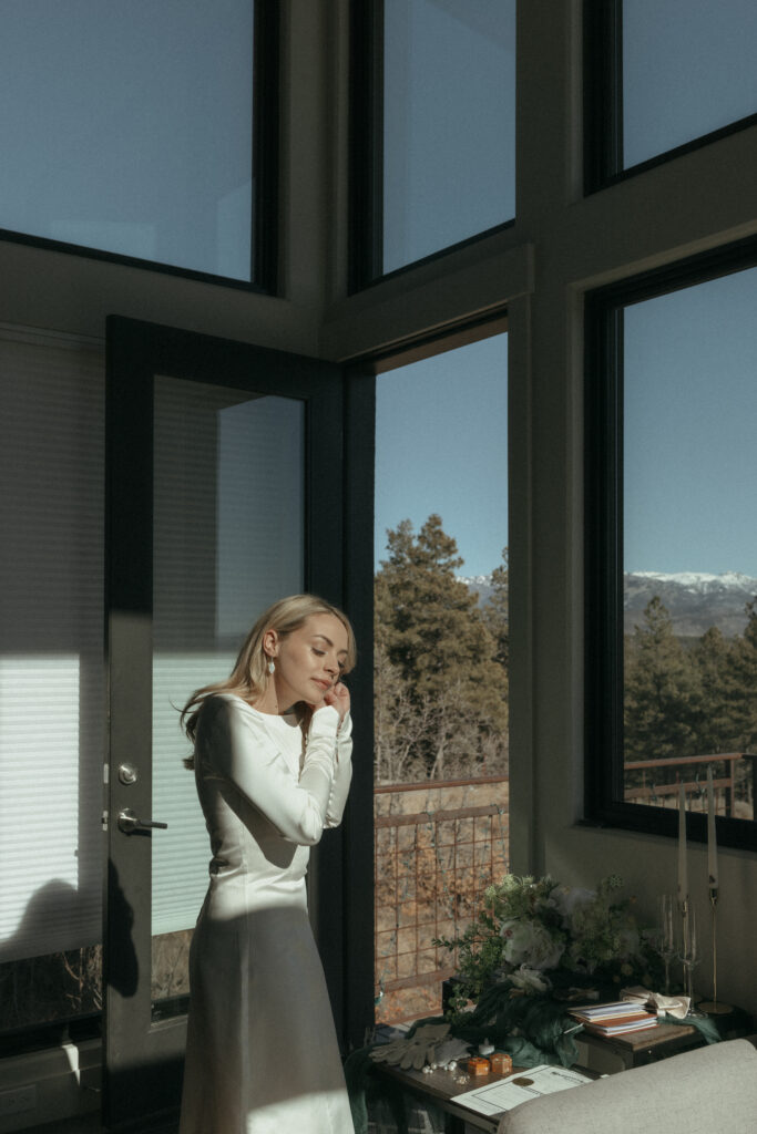 Bride putting her earrings in standing beautifully lit from the sun