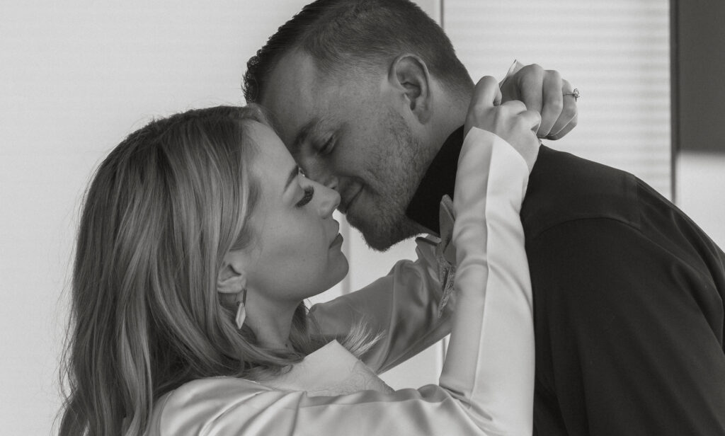 Bride and groom almost kissing as she helps secure his bowtie 