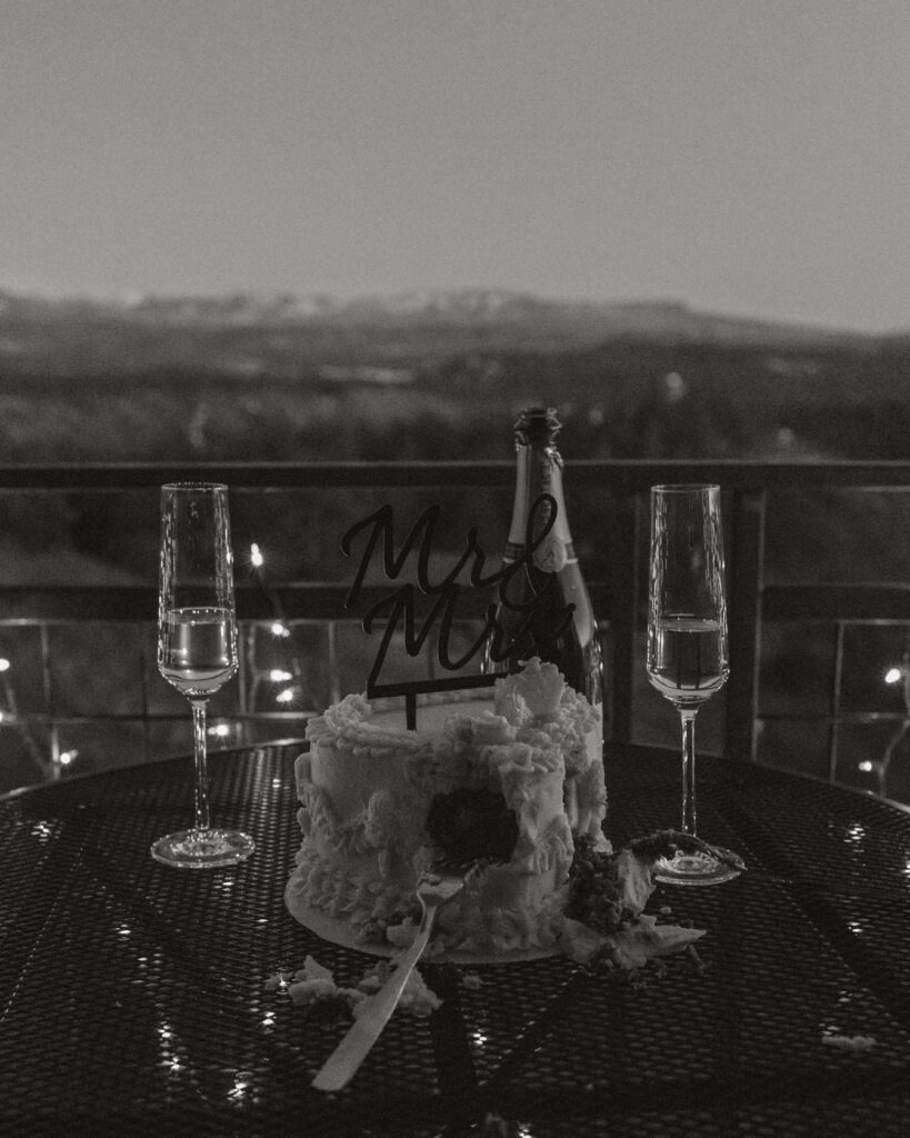 Wedding cake and champagne bottle sitting on balcony in mountains