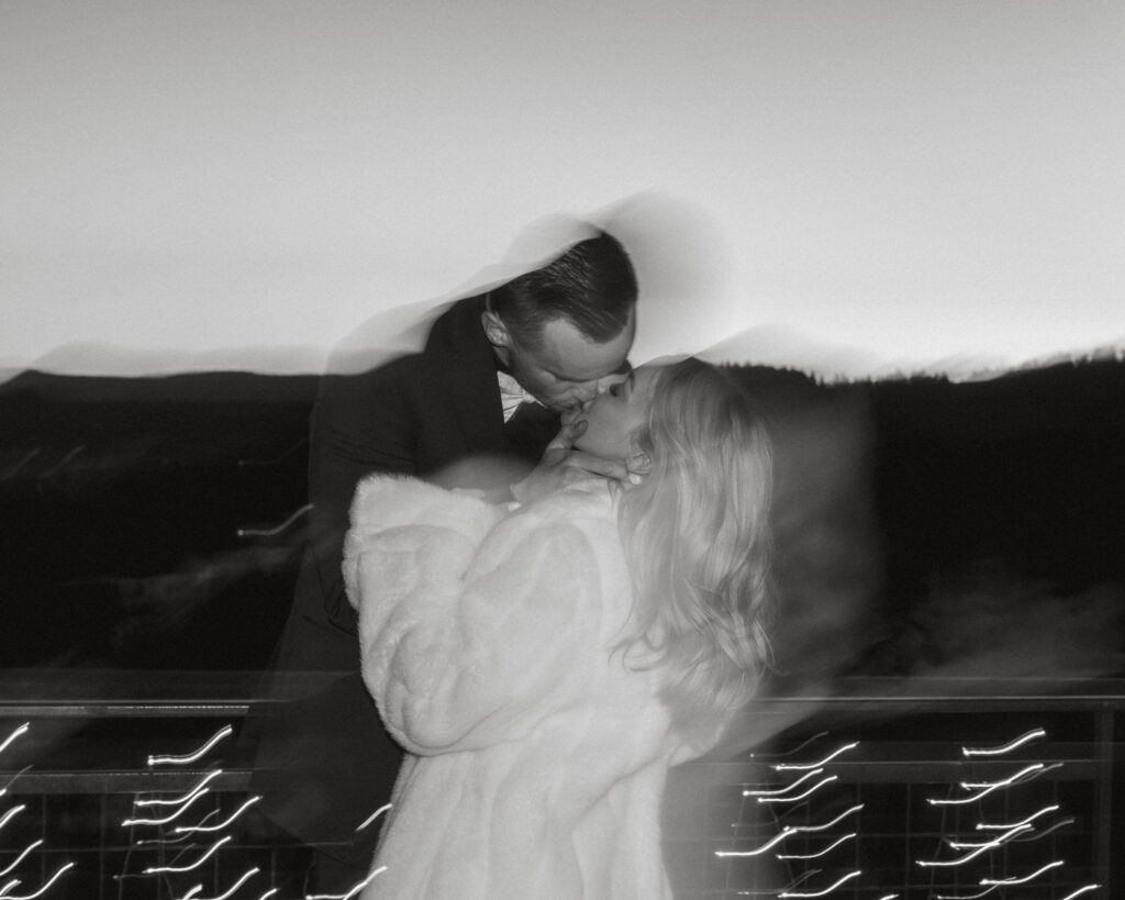 Black and white shutter drag photo of bride and groom kissing