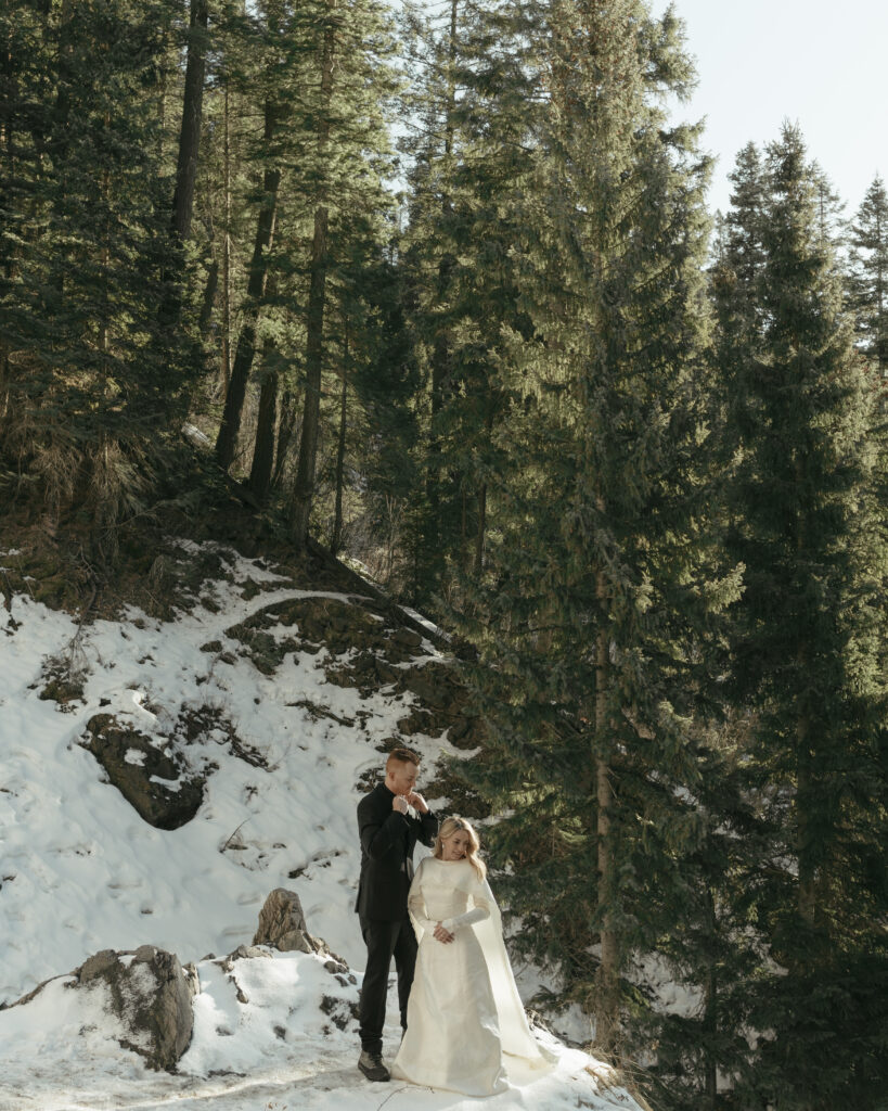Bride and groom standing in the snow on top of the mountain trail in Pagosa Springs, Colroado