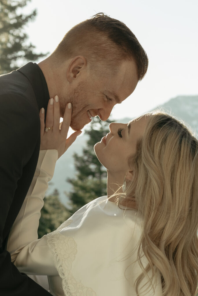 Groom smiling as his bride leans into kiss him at their snowy mountain elopement 