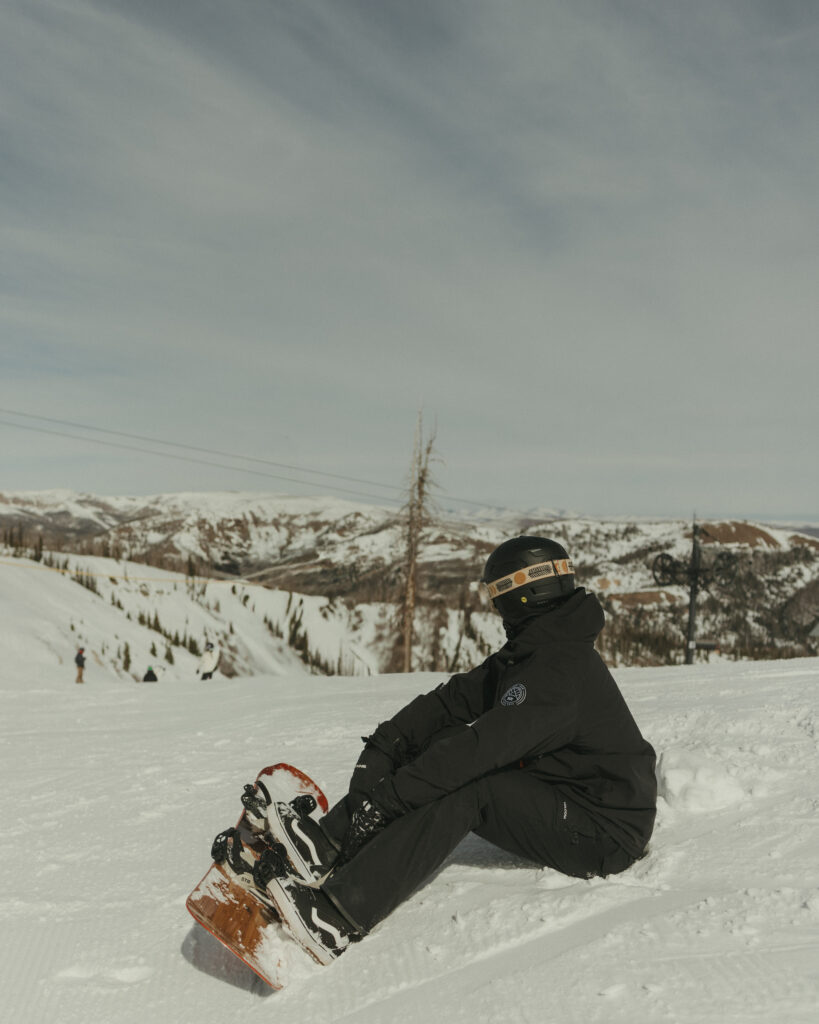 Groom strapping into snowboard at the top of the ski mountain at Wolf Creek Ski 