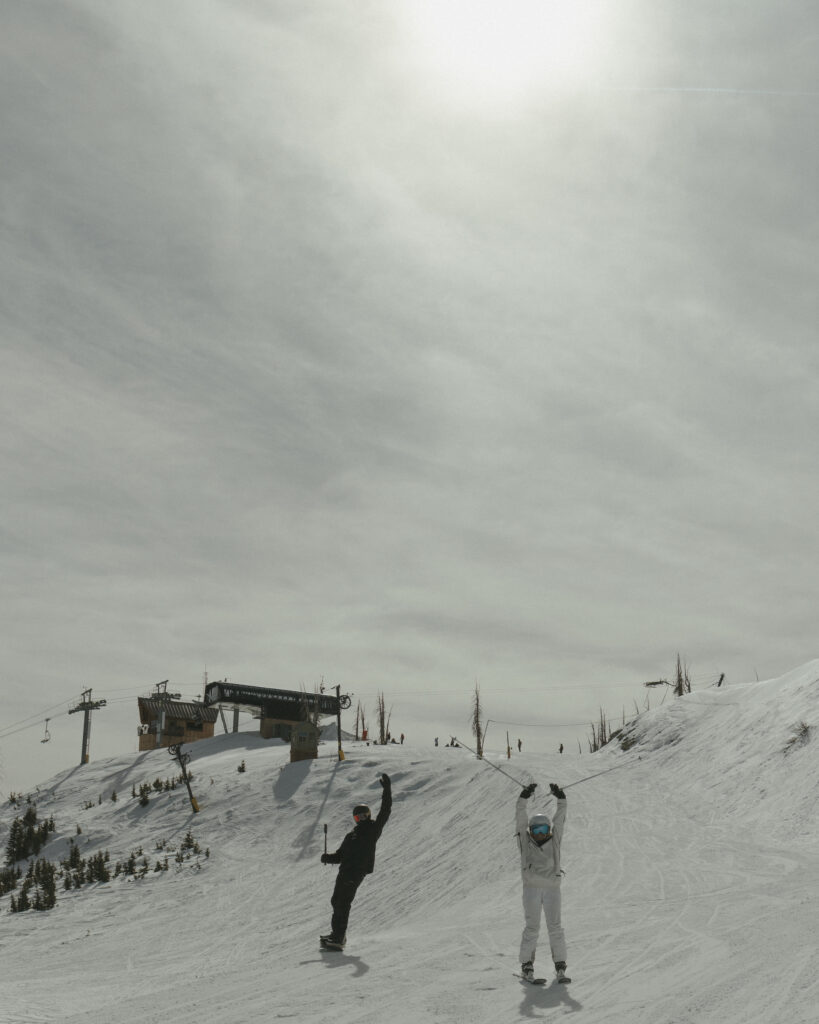 Bride and Groom throwing their hands up in excitement as they ski down the mountain at Wolf Creek Ski Area in Pagosa Springs, Colorado