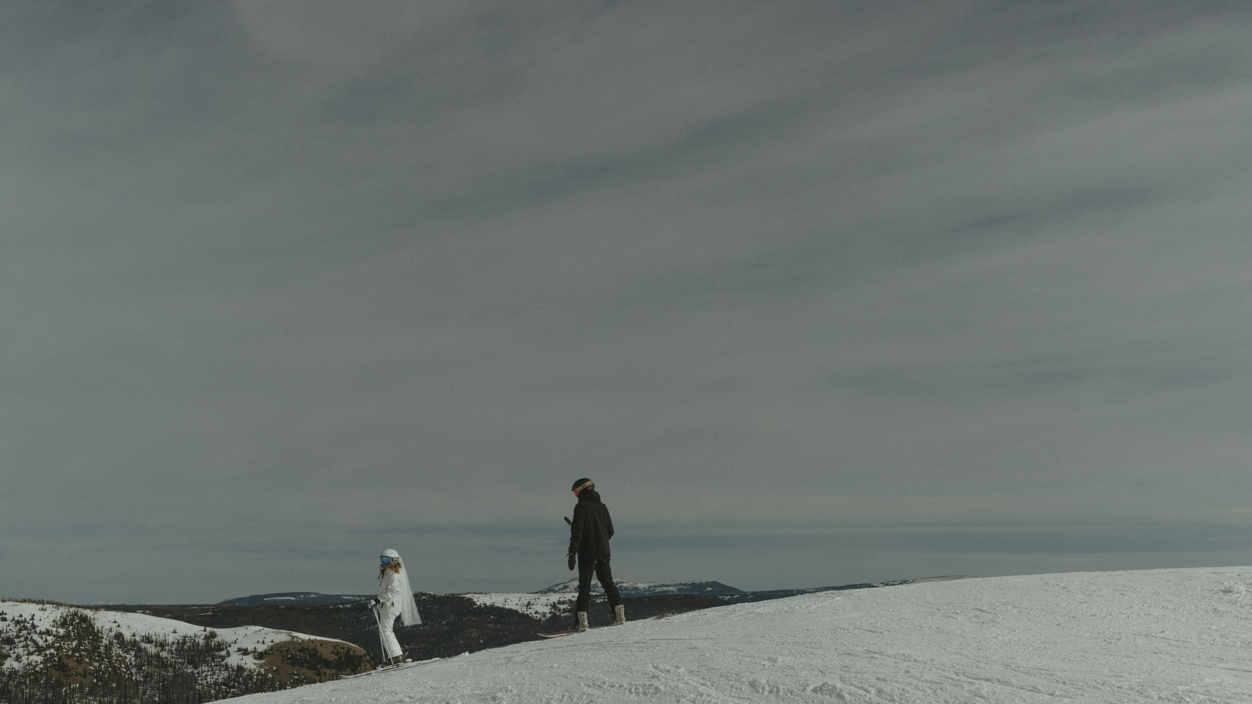 Bride and Groom Skiing and Snowboarding down the mountain on their elopement day at Wolf Creek Ski Area in Pagosa Springs, Colorado