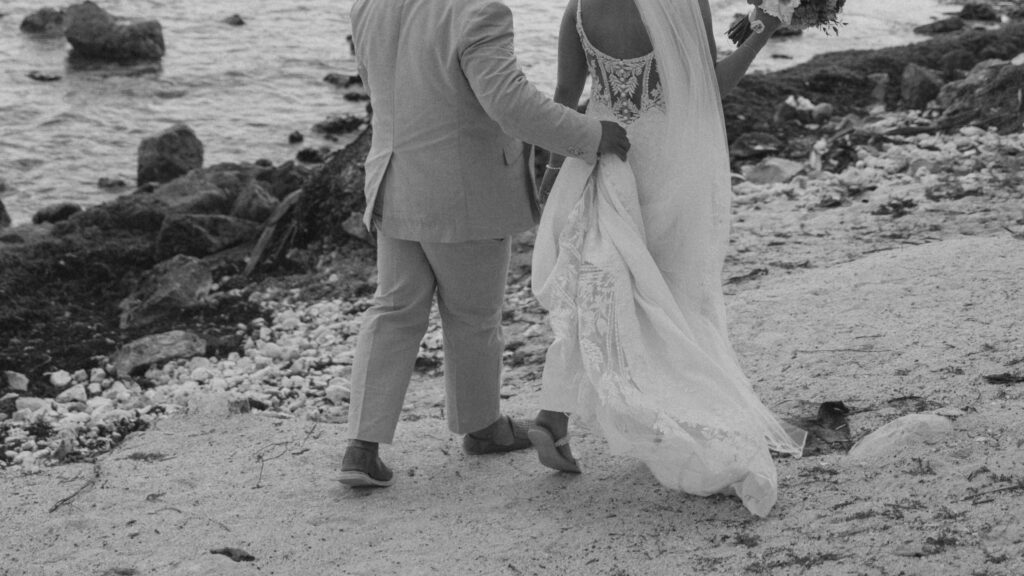 bride and groom walking along beach during wedding portraits, natural movement and candid moment wedidng photography