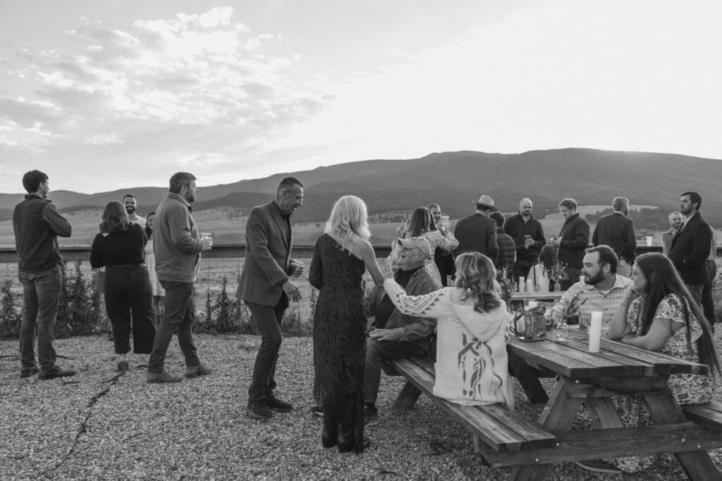 wedding guests mingling outdoors during cocktail hour with mountain view, relaxed timeline moment