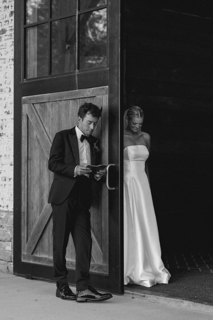Groom reading letter before ceremony outside barn doors at Trinity View Farm wedding in Franklin Tennessee