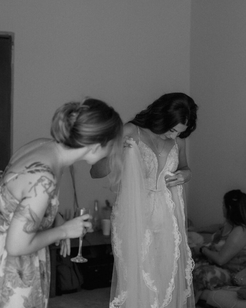 bride putting on wedding dress with bridesmaid emotional getting ready moment Mexico destination wedding