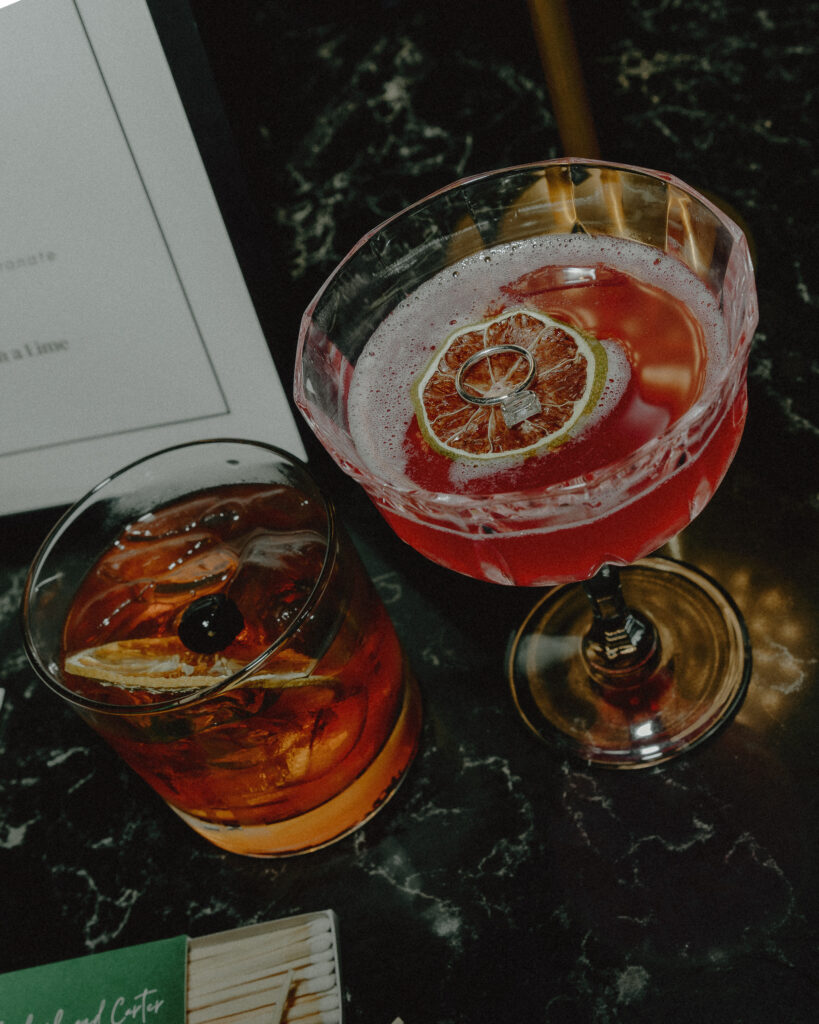 fun detailed shot of wedding ring sitting on top of a lime in a signature cocktail with an old fashion whiskey drink