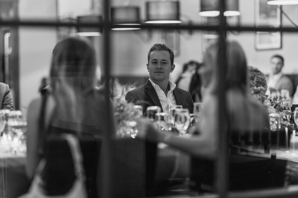 photograph of man sitting at dinner table during reception