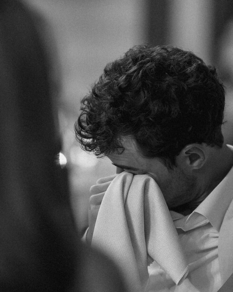 emotional black and white photo of groom wiping away his tears during speeches