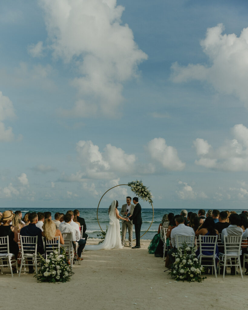 beach wedding ceremony Mexico ocean backdrop bride and groom exchanging vows tropical destination