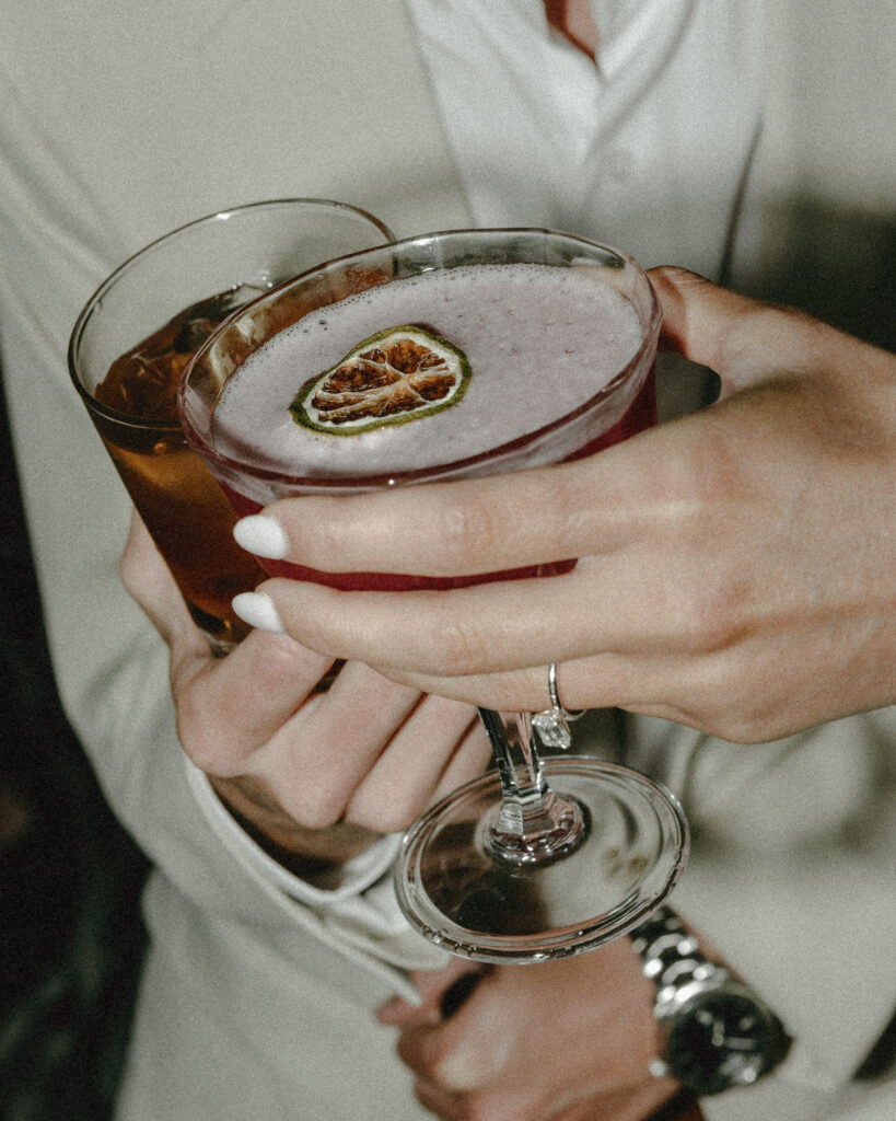 bride and groom holding their signature cocktails together
