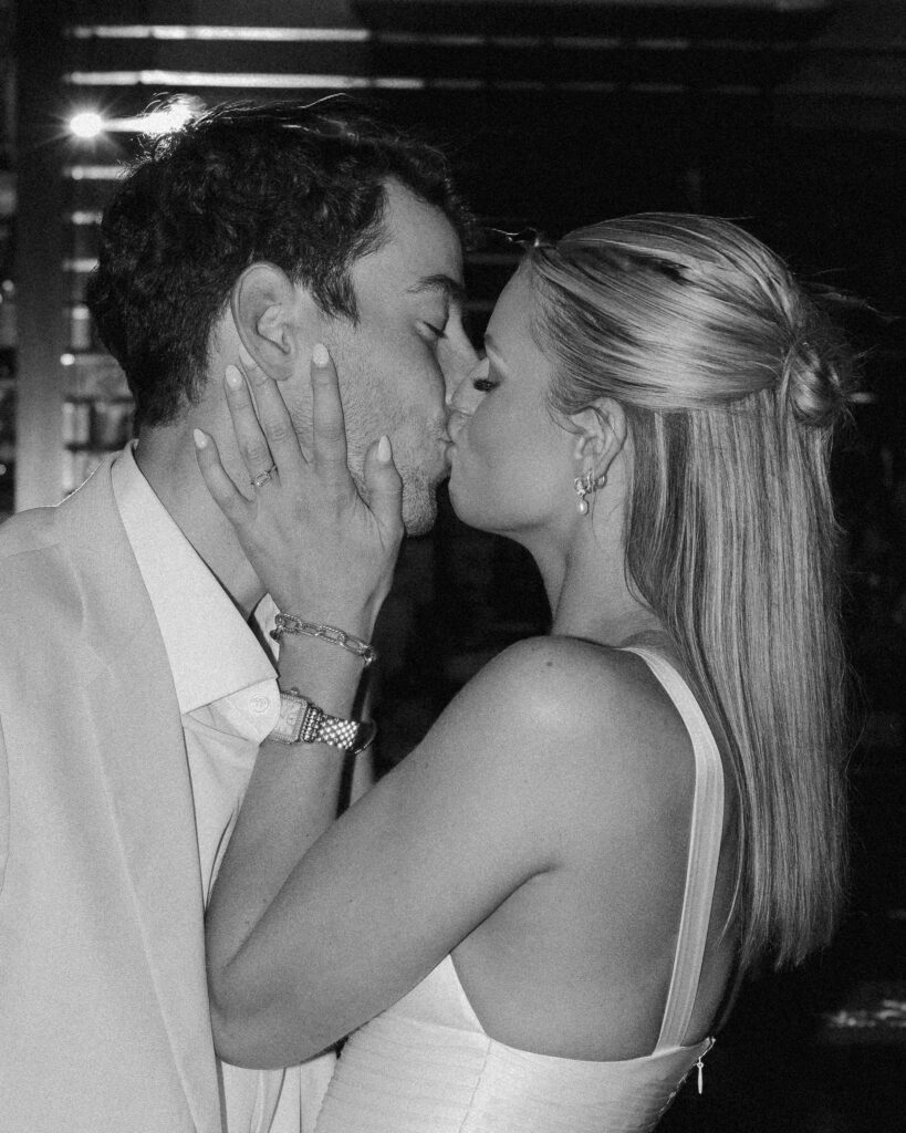 black and white photograph of bride grabbing and kissing the groom