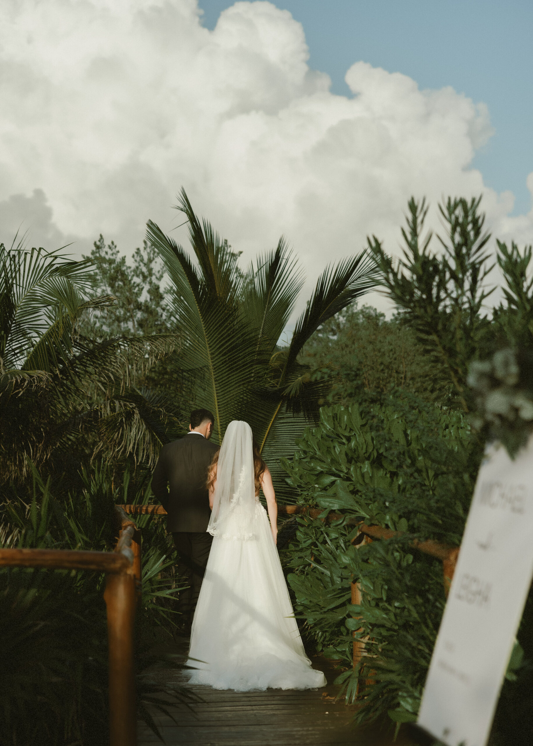 newlyweds walking away tropical garden path destination wedding Mexico cinematic romantic moment