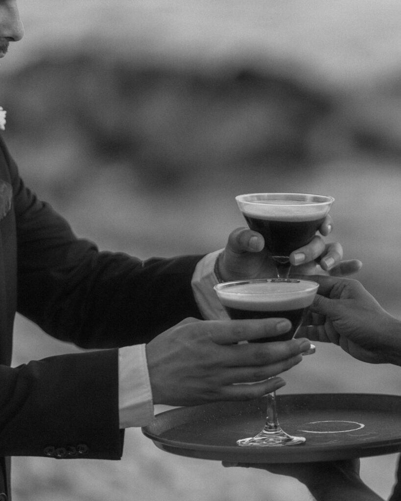 cocktail toast close up hands holding espresso martinis black and white wedding reception