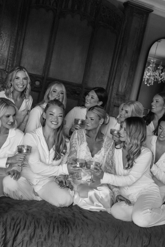 Bride surrounded by bridesmaids in matching white outfits toasting before Trinity View Farm wedding