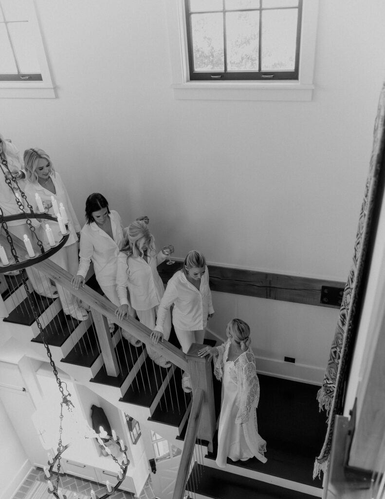 Bride and bridesmaids walking down staircase in bridal suite at Franklin Tennessee wedding venue