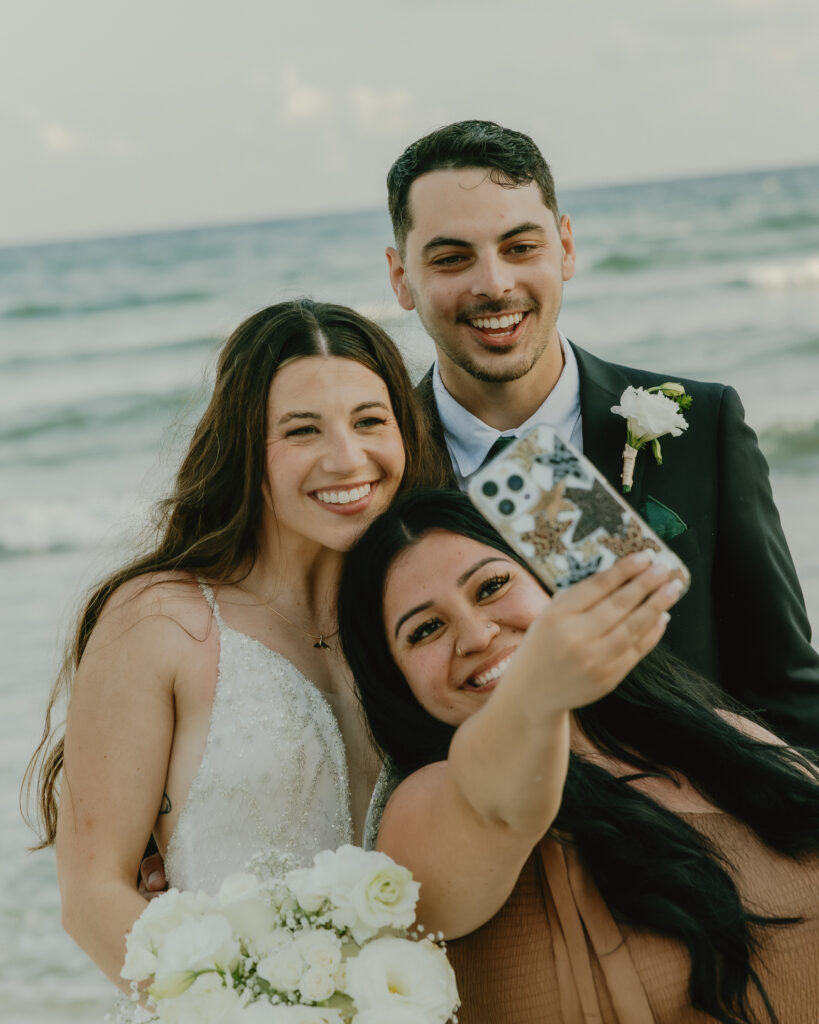 bride and groom taking selfie with friends beach wedding Mexico candid joyful moment