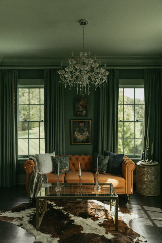 The bridal suite at Trinity View Farm with a fun velvet orange couch, cowhide rug, and beautiful green walls 