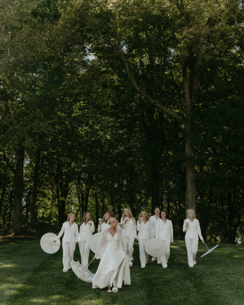 Bride and bridesmaids walking through trees with parasols during elegant Franklin Tennessee wedding