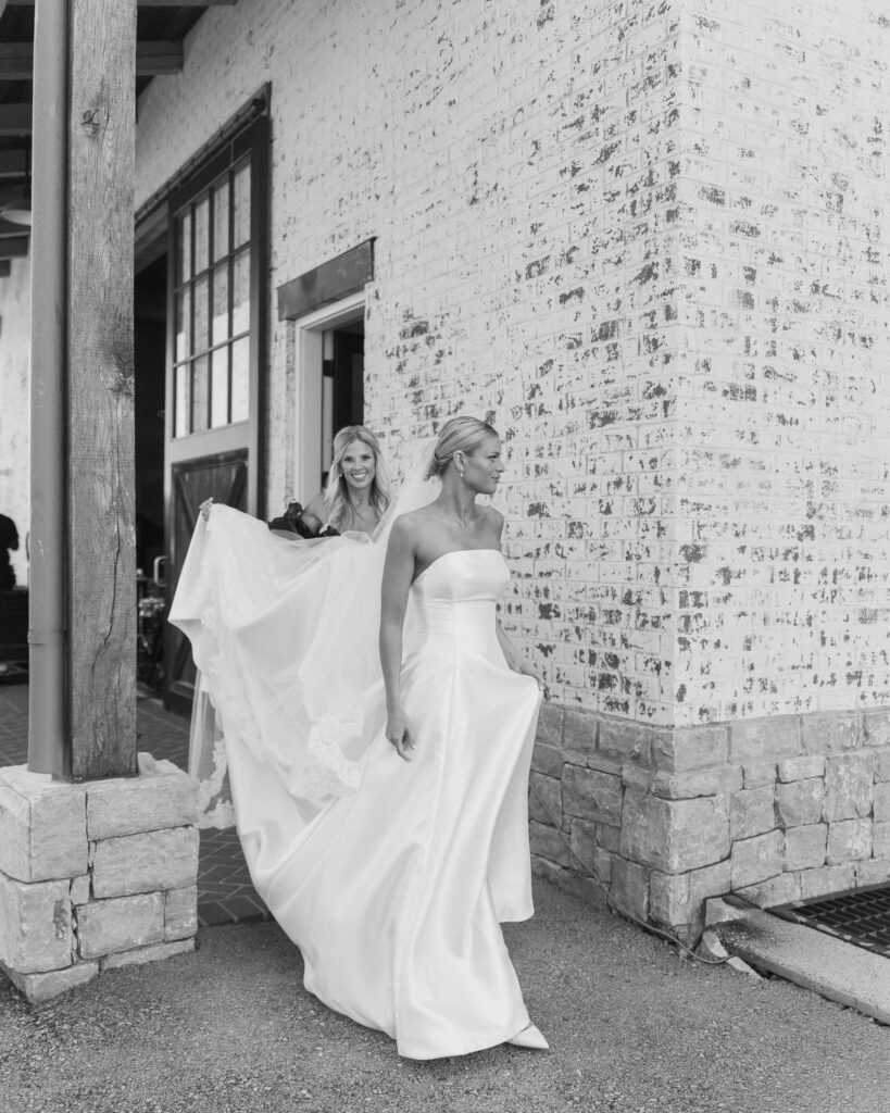 Bride walking outside venue with mom holding dress at Trinity View Farm wedding