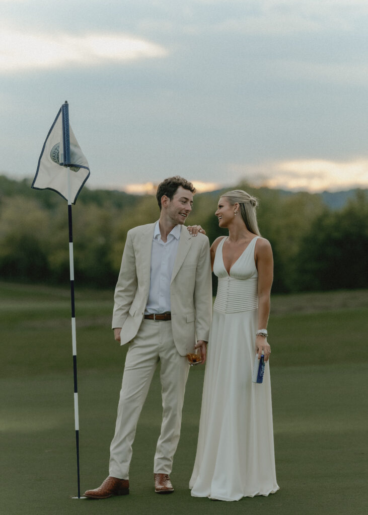 bride and groom looking at each other smiling standing on the golf course