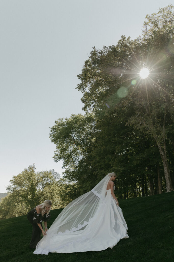 Bride with long veil and train walking across hillside at Trinity View Farm wedding in Franklin Tennessee