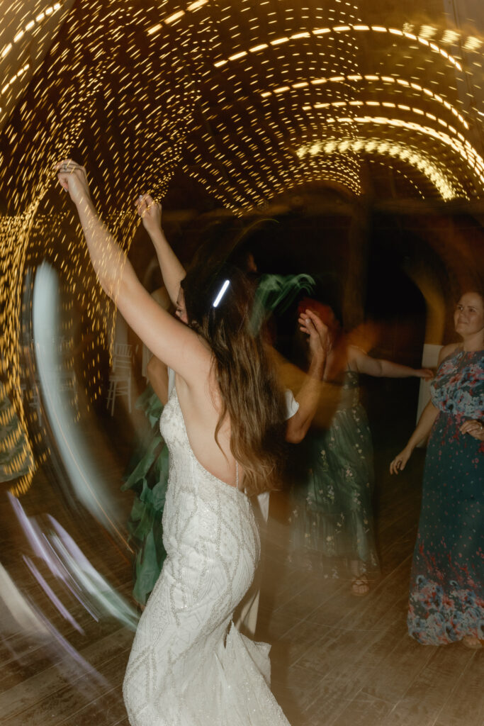 bride dancing with arms raised wedding reception party destination wedding Mexico celebration energy