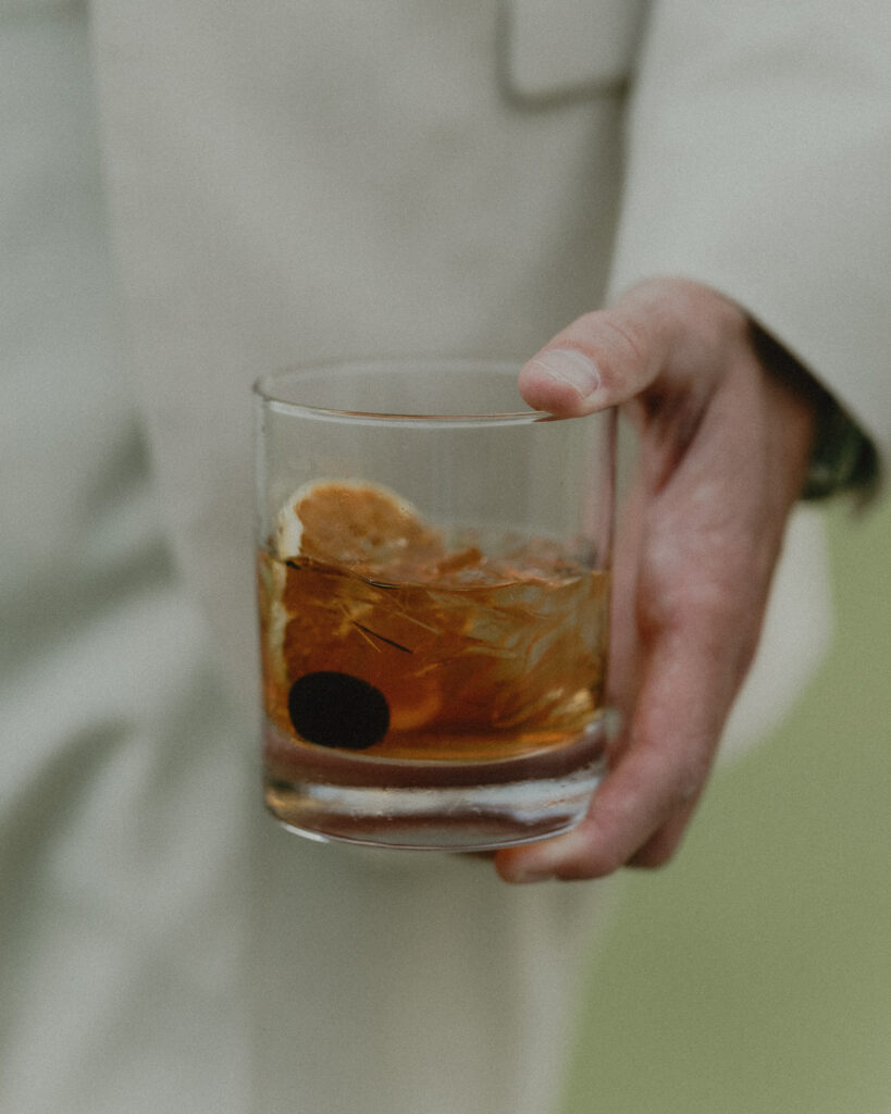 groom hold his old fashion whiskey drink