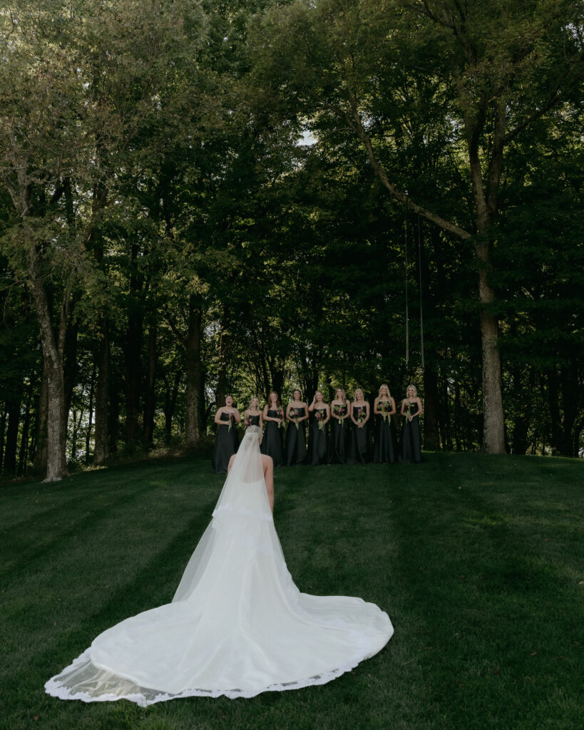 Bride facing bridesmaids lined along hill for a first look reaction at Trinity View Farm wedding in Franklin TN
