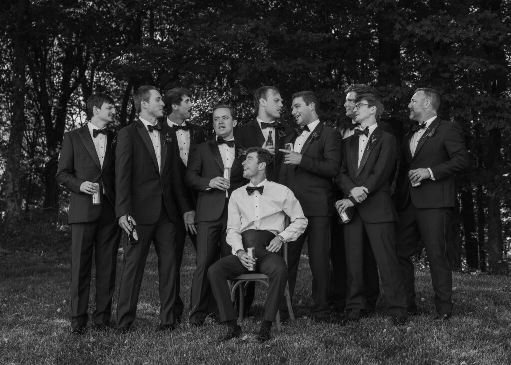 Groom and groomsmen in black tuxedos posing together outdoors at Franklin Tennessee wedding