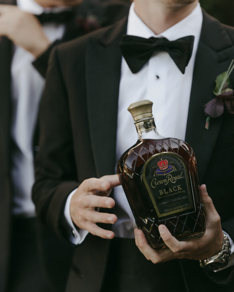 Groom holding Crown Royal bottle during wedding day at Franklin Tennessee wedding venue