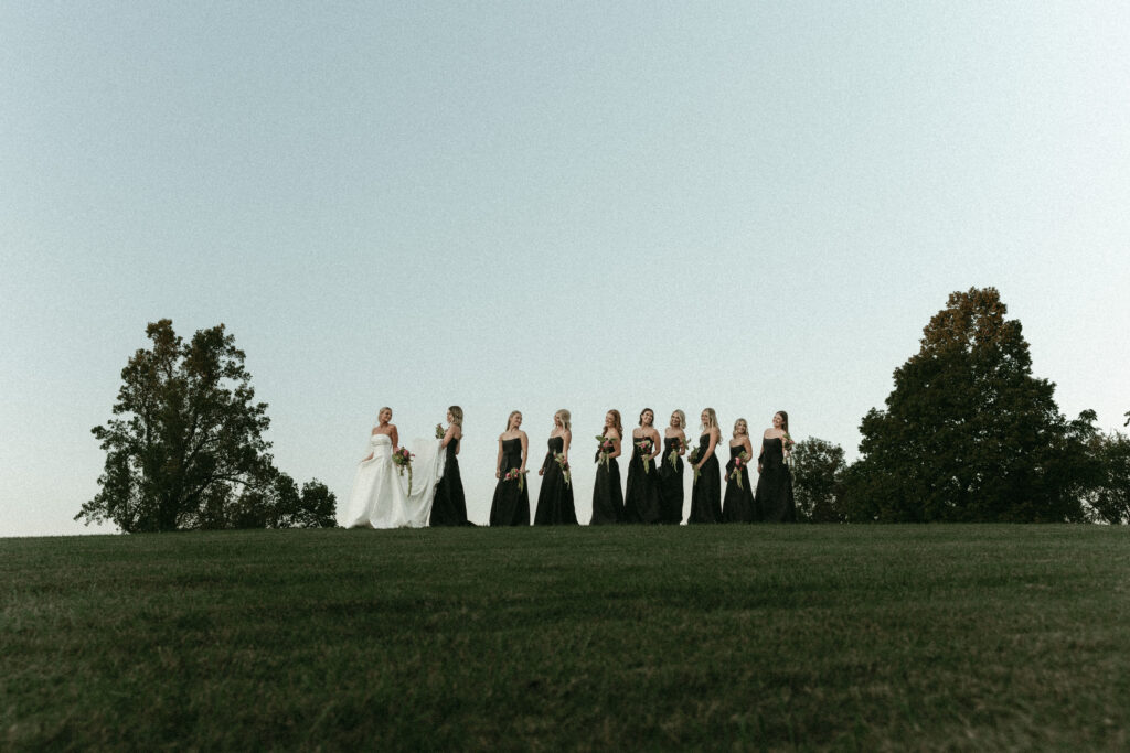 Bride and bridesmaids walking in a line on top of a beautiful lush green hill in franklin tennessee
