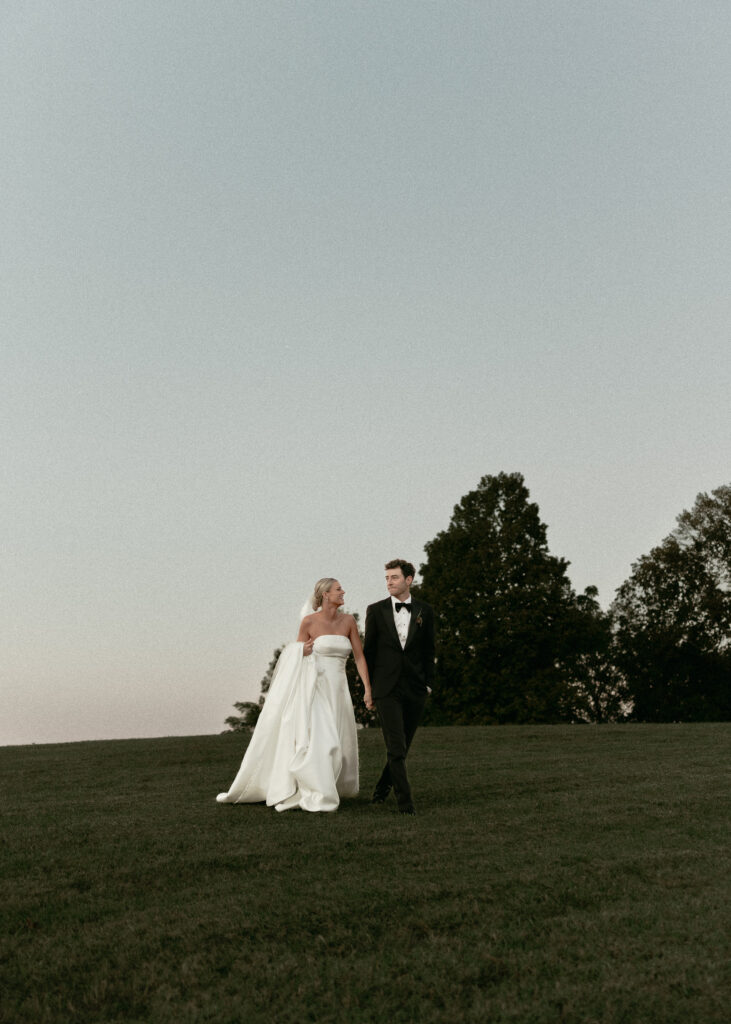 Bride and groom walking together across hillside at Trinity View Farm wedding in Franklin Tennessee