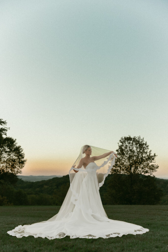 Bride and groom holding veil during sunset portraits at Trinity View Farm wedding