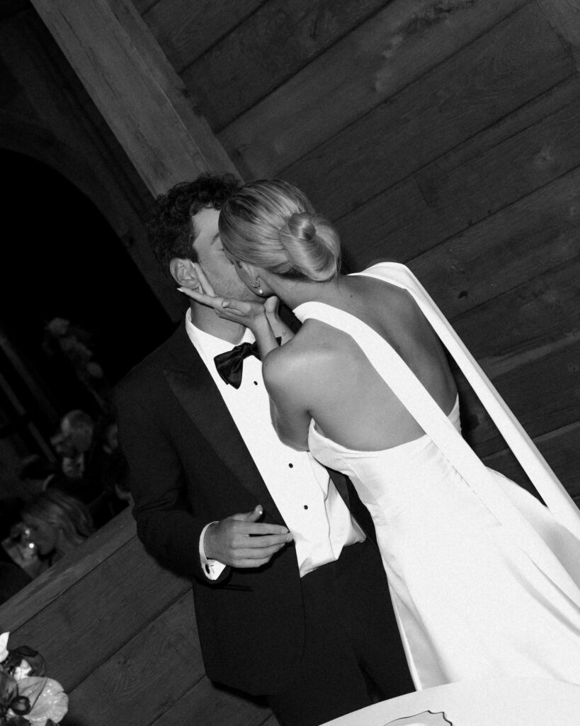 Bride kissing groom on cheek during wedding reception at Trinity View Farm