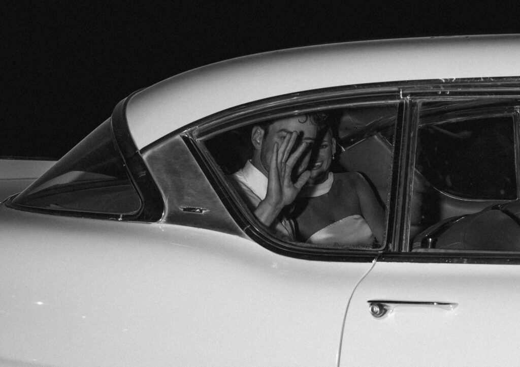 Bride and groom waving from inside getaway car after wedding reception in Franklin Tennessee
