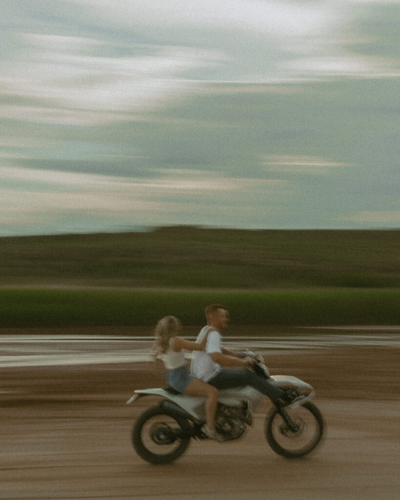 Motion blur engagement photo of couple riding motorcycle in Texas desert