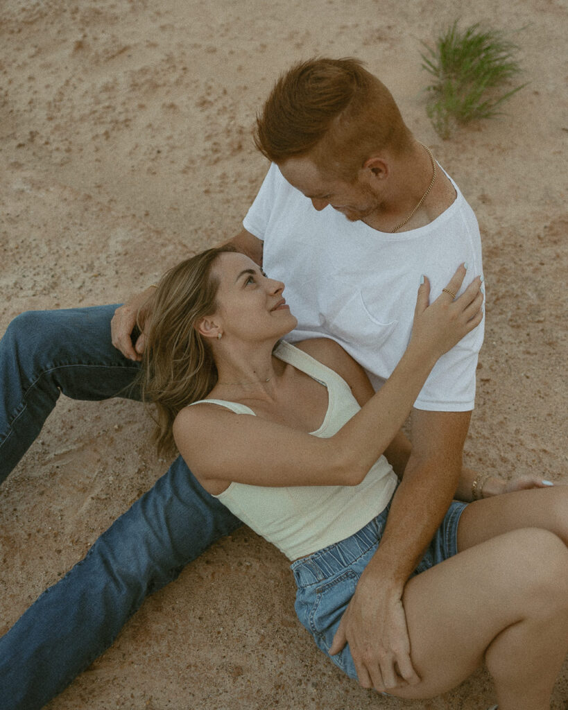 Overhead engagement photo of couple laying in sand embracing in Amarillo Texas