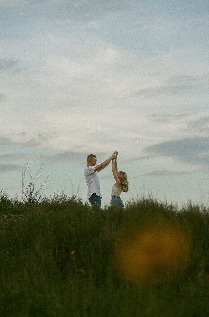 Couple dancing and spinning in tall grass during golden hour engagement session in Texas