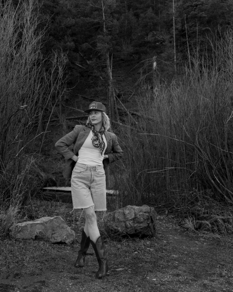 photographer portrait of woman in western outfit standing outdoors in natural landscape, cinematic wedding photography style