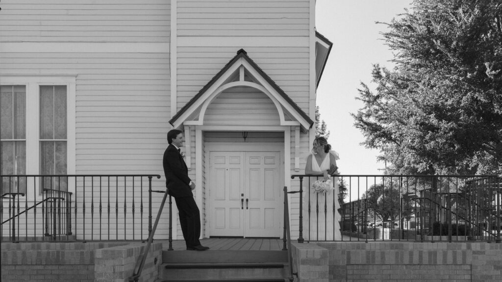 Bride and groom standing on the railing outside of an old historic building in downtown Amarillo Texas
